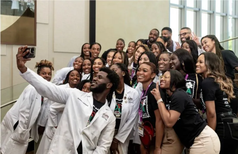 SNDA members in lab coats taking a group selfie - dental students community